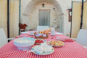 einem Tisch mit einem roten karierten Tischtuch mit Lebensmitteln darauf in der Unterkunft Trulli Borgo Lamie in Locorotondo