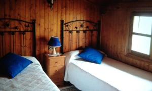 Un dormitorio con dos camas y una lámpara y una ventana. en El bordón de Noriega, en Noriega