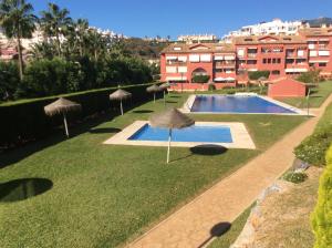 a lawn with umbrellas and a swimming pool at Agua Marina exklusiv apartment in Benalmádena