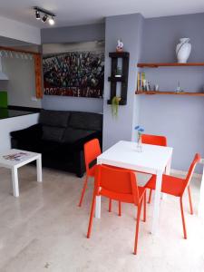 ein Wohnzimmer mit einem weißen Tisch und orangefarbenen Stühlen in der Unterkunft Dénia Centro Puerto in Denia