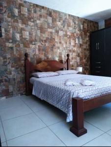 a bed in a room with a brick wall at Loft da Montanha (A 8min do centro) in Nova Friburgo
