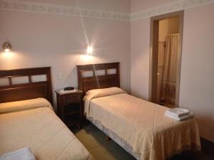 a hotel room with two beds and a mirror at Hotel Alonso in Río Gallegos
