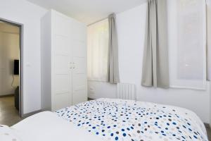 una camera da letto bianca con un letto a pois blu di Heptagone a Saint-Quentin