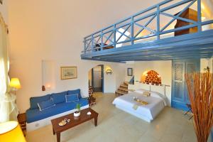 a living room with a blue couch and a bed at Tamarix Del Mar Suites in Kamari