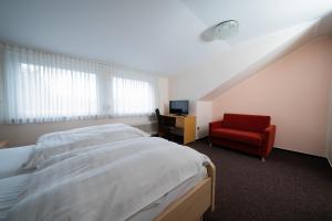 瓦倫多夫的住宿－Hotel Emshof，一间卧室配有一张床和一张红色椅子