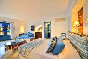a bedroom with a large bed with blue pillows at Tamarix Del Mar Suites in Kamari