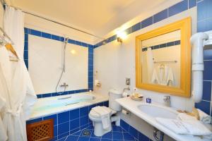 a blue bathroom with a tub and a sink and a toilet at Tamarix Del Mar Suites in Kamari