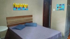 a bedroom with a bed with blue pillows on it at Chacara Estrela do Mar in Peruíbe