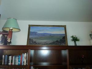 a painting on a wall above a book shelf with a lamp at Thorshamar - Car Included in Reykjavík