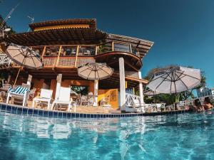 um resort com uma piscina com cadeiras e guarda-sóis em Passárgada Pousada e Restaurante em Morro de São Paulo