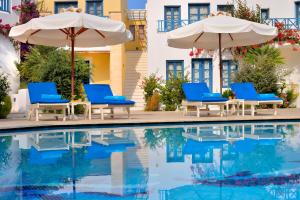a pool with chairs and umbrellas next to a building at Tamarix Del Mar Suites in Kamari