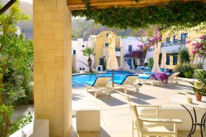 a patio with chairs and a swimming pool at Tamarix Del Mar Suites in Kamari