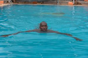 a man is swimming in a swimming pool at Falcon heights Hotel in Nanyuki