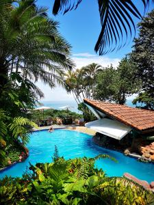 a pool at a resort with blue water and palm trees at Si Como No Resort & Wildlife Refuge in Manuel Antonio