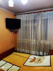 um quarto com uma cama, uma televisão e uma janela em Просторная квартира в центре Тирасполя! em Tiraspol
