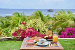 einen Tisch mit einem Frühstück mit Obst und Saft und dem Meer in der Unterkunft Villa Guadeloupe Saint François Accès Mer Piscine IGUANA BAY - Villa Zagadi in Saint-François