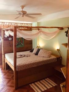 a bedroom with a canopy bed with a ceiling at Alibaba‘s Seabreeze in Castara