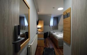 een kleine kamer met een bed en een spiegel bij Dolce Vita Panzió in Miskolc