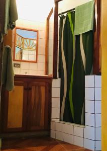 a bathroom with a green shower curtain and a mirror at Alibaba‘s Seabreeze in Castara