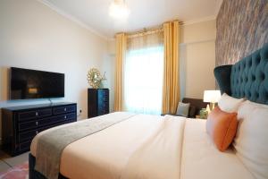 a bedroom with a large bed and a television at Two Continents Holiday Homes - Sea and Palm Jumeriah view Four Bedroom Apartment -Free Airport Pick-up in Dubai