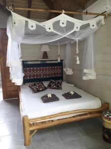 1 dormitorio con cama con dosel y almohadas en The BlueBamboo, en Le Moule