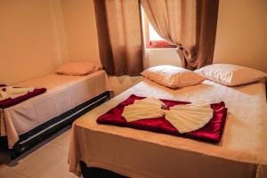 two beds in a room with a dress on them at Pousada Casa Grande in Barra do Garças