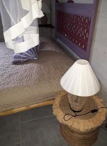 een lamp op een mand naast een bed bij The BlueBamboo in Le Moule