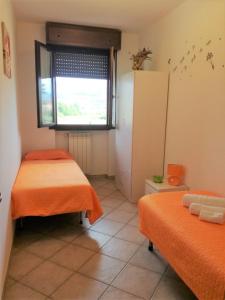 Habitación con 2 camas, ventana y nevera. en Casa Lella, en Montecatini Terme