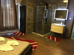 a bathroom with a shower and a bed and a sink at Hotelwhite Family Gjilan in Gjilan