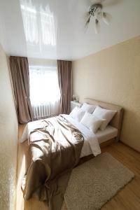 a bedroom with a bed with white sheets and a window at PaulMarie Apartments on Molodeznaya in Soligorsk