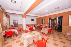 a dining room with tables and red chairs at Pemicsa Hotel Accra in Spintex
