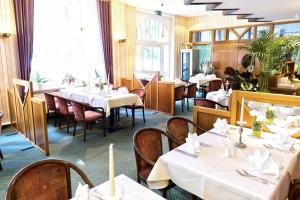 a restaurant with white tables and chairs and windows at Parkhotel Meerane in Meerane