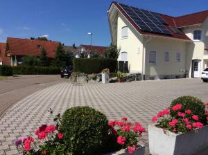 a brick driveway with flowers and a house with a solar roof at Ferienwohnung Kunst in Mahlberg