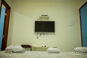 a flat screen tv on the wall of a bedroom at Suítes Da Vila 152 in Praia do Forte