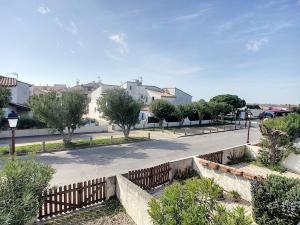 eine Straße mit einem Zaun, Bäumen und Gebäuden in der Unterkunft Superbe Duplex aux Saintes terrasse plein sud 3*** in Saintes-Maries-de-la-Mer