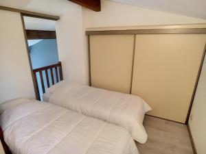 two beds in a room with white sheets at Superbe Duplex aux Saintes terrasse plein sud 3*** in Saintes-Maries-de-la-Mer