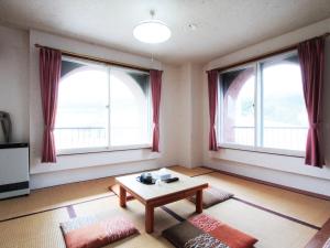 a living room with two windows and a coffee table at Hotel Moc in Myoko