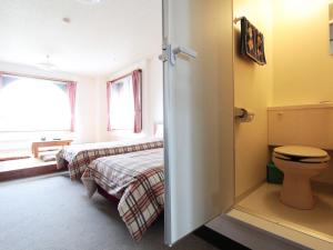 a bathroom with two beds and a toilet in it at Hotel Moc in Myoko