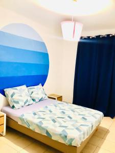 een slaapkamer met een bed met een blauwe muur bij Nawalie in Pointe-à-Pitre