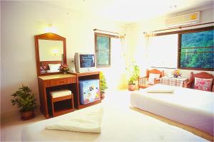a hotel room with a bed, desk, mirror and television at J Mansion in Ao Nang Beach