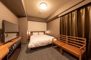 a hotel room with a bed and a television at Dormy Inn Kawasaki Natural Hot Spring in Kawasaki