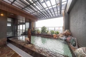 a swimming pool in a building with a large window at Dormy Inn Kawasaki Natural Hot Spring in Kawasaki