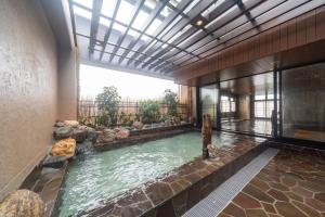 a swimming pool in a building with a large window at Dormy Inn Kawasaki Natural Hot Spring in Kawasaki