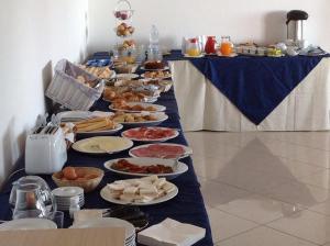 ein langer Tisch mit vielen Teller Essen drauf in der Unterkunft Hotel Castello Budoni in Budoni