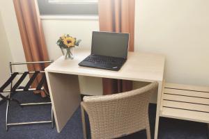 a laptop computer on a desk with a vase of flowers at Best Deal Airporthotel Weeze in Weeze