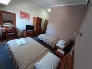 Habitación de hotel con 2 camas y escritorio en Sin-Kom Hotel Garni, en Pirot