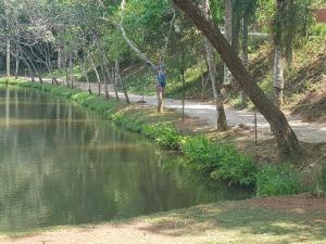 a person standing on a path next to a river at LINDA CHACARA EM CONDO A 40 MIN DE SP com piscina climatizada, churrasqueira, wifi, 5 quartos e muita natureza in Cajamar