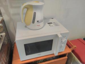 a microwave with a tea kettle on top of it at Sakai Guest House AMAMI（堺ゲストハウス奄美） in Setouchi