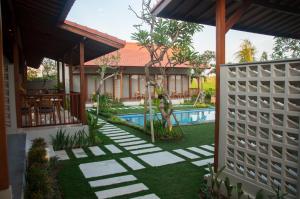 a backyard with a swimming pool and a house at Omorich Bali Guest House in Canggu