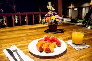 a plate of fruit on a table with a glass of orange juice at Omorich Bali Guest House in Canggu